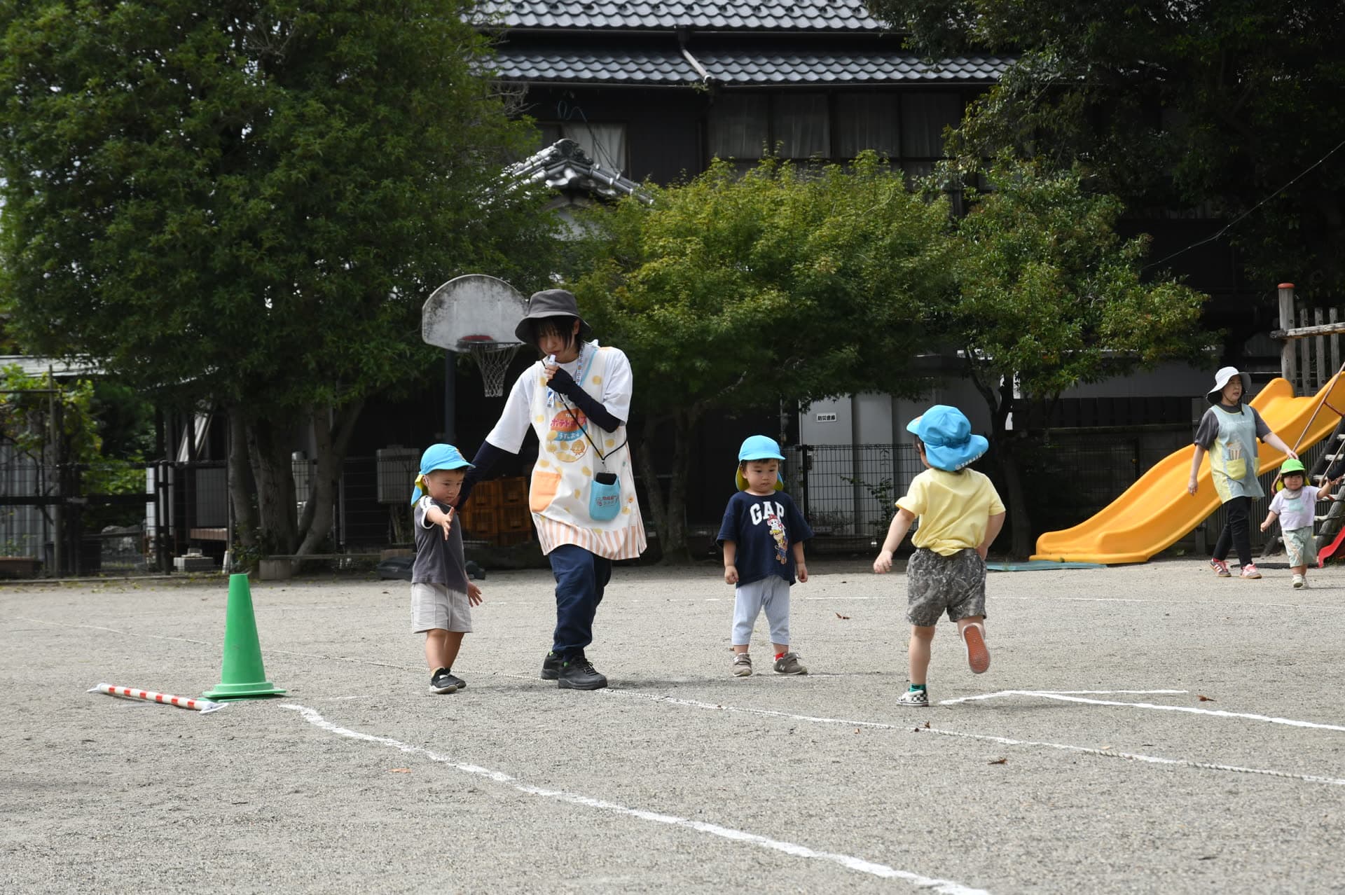 園庭で先生とかけっこをするこどもたち